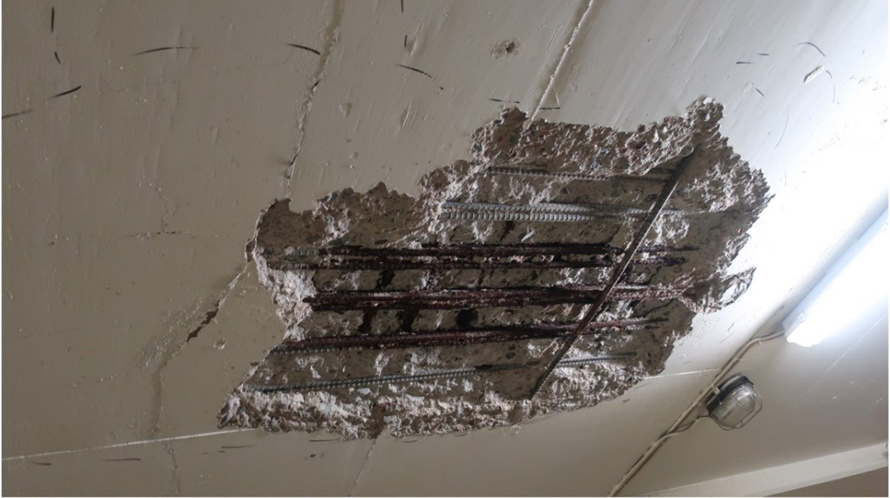 Betongen i ett tak har skadats och blottlagt ett stort hål där även armeringen blivit synlig.