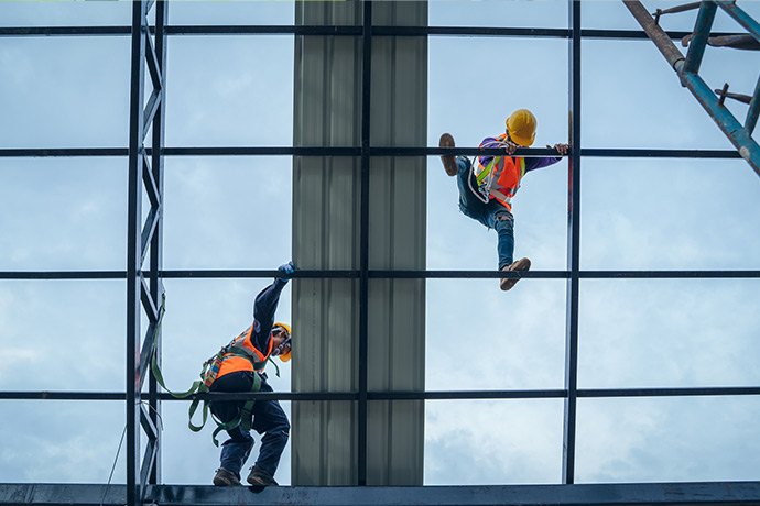 To byggningsarbeidere er sikret mens de jobber på åpent tak. Foto.
