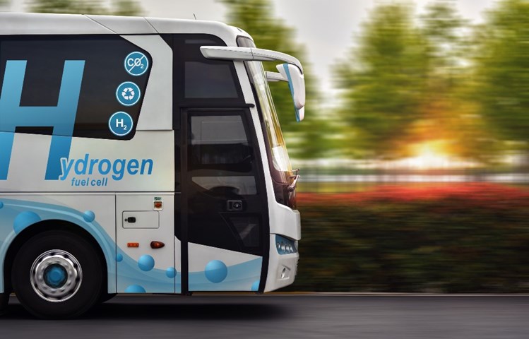 En buss som kör på en väg med text att den drivs med hydrogen (vätgas). 
