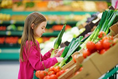 Kind op de groenteafdeling in de supermarkt