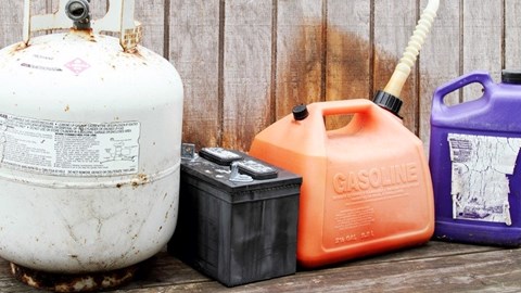 Behållare för kemikalier av olika slag: gasbehållare, bilbatteri, bensindunk och plastdunk för annan vätska.
