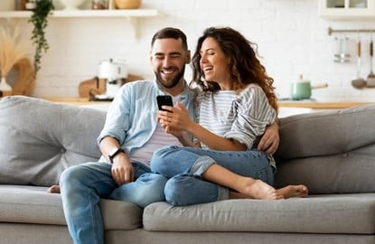Man and woman sitting together on the couch looking at a phone