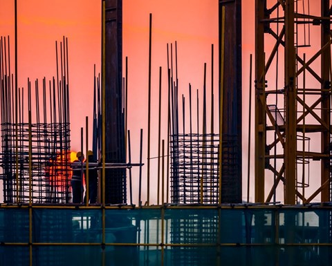 Steel building site with builders and sunset
