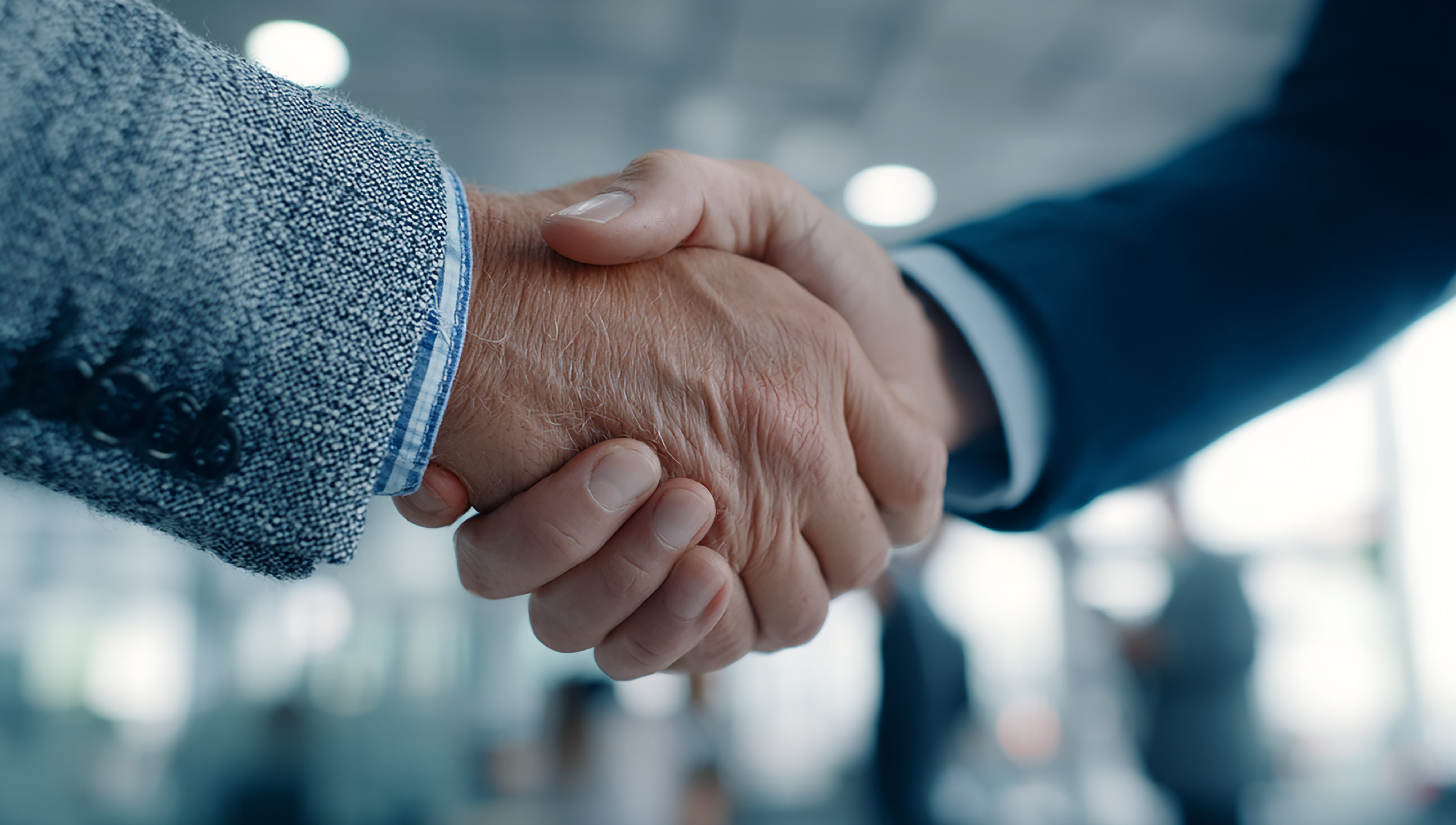 Primer plano de dos personas dándose la mano en un entorno empresarial