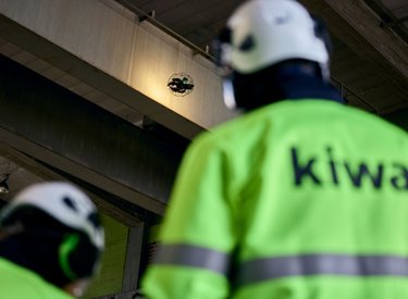 Kiwa employees in high-visibility jackets observe a drone inspecting industrial infrastructure indoors