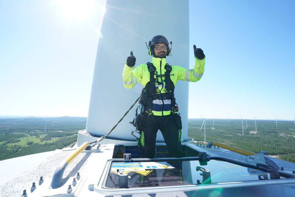 Kiwa inspector performing wind turbine inspecton giving two thumbs up while standing on the wind turbine