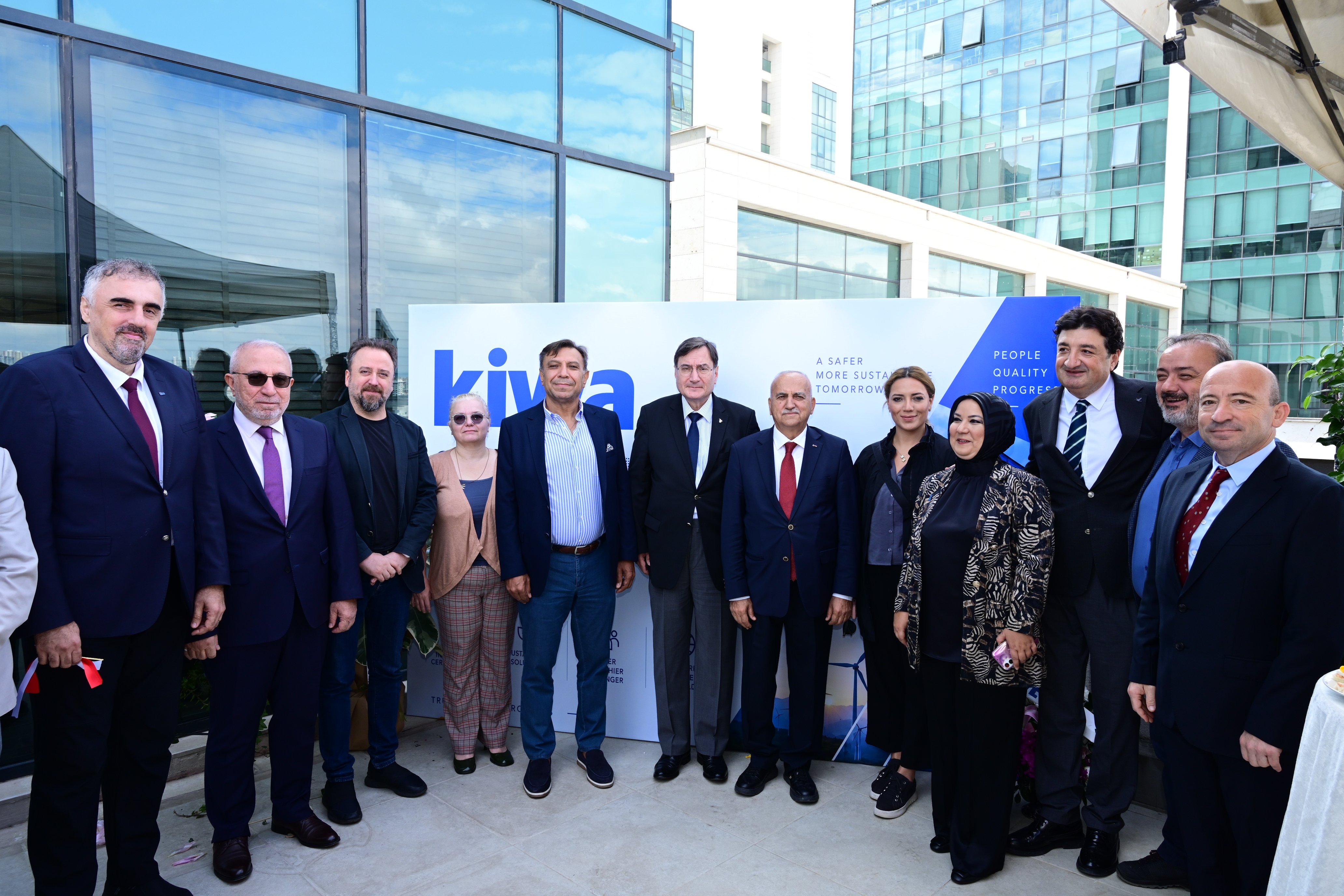 Ribbon-cutting ceremony with a group of people outside a modern office building, with glass towers and a canopy overhead.