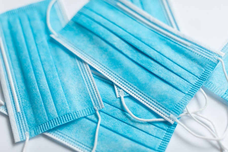 Stack of blue disposable face masks on a white background.