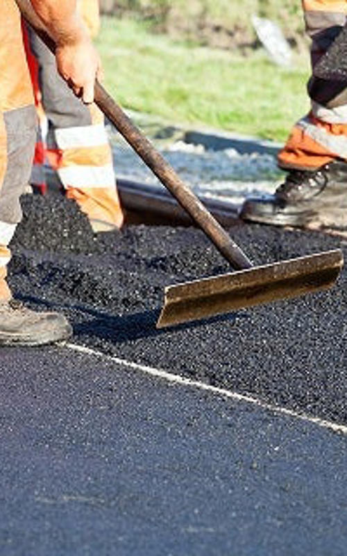 Road construction in operation with workers paving a road with asphalt