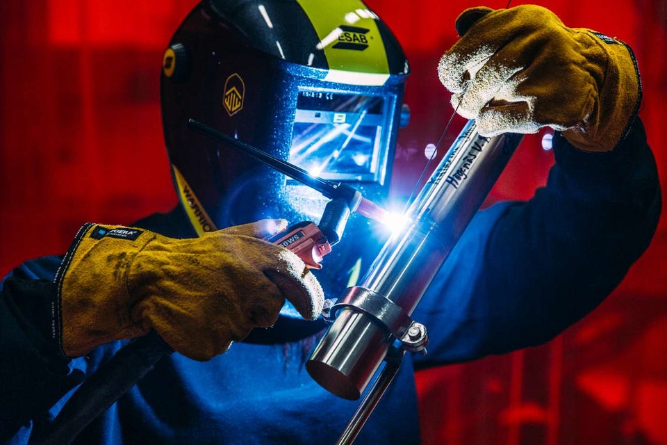 Suvirintojas su apsaugine kauke ir storomis pirštinėmis atlieka metalo suvirinimo darbus, matomos ryškios kibirkštys – suvirinimo darbų priežiūros meistro ir koordinatoriaus mokymai