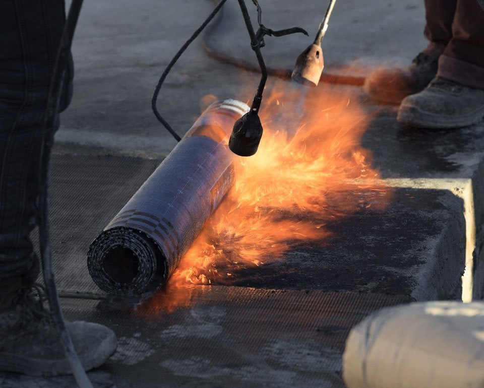 Utførelse av varmt arbeid. Påføring av takpapp ved bruk av brenner.