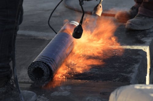 Utførelse av varmt arbeid. Påføring av takpapp ved bruk av brenner.