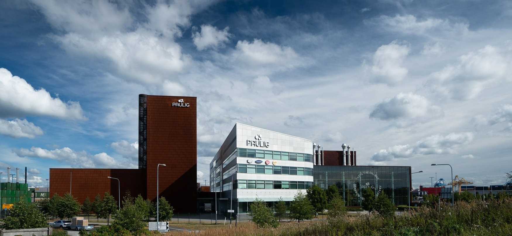 Modern Paulig office building with a white and brown facade under a cloudy sky.