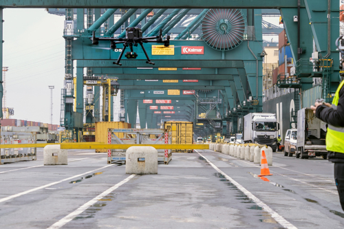 Kiwa drone pilot operating a drone in a busy shipping port with cranes and cargo containers, enhancing logistics and security operations