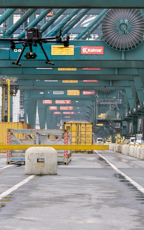 Kiwa drone pilot operating a drone in a busy shipping port with cranes and cargo containers, enhancing logistics and security operations