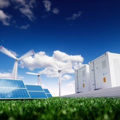 Solar panels and wind turbines beside a hydrogen energy storage container on a grassy field under a blue sky.