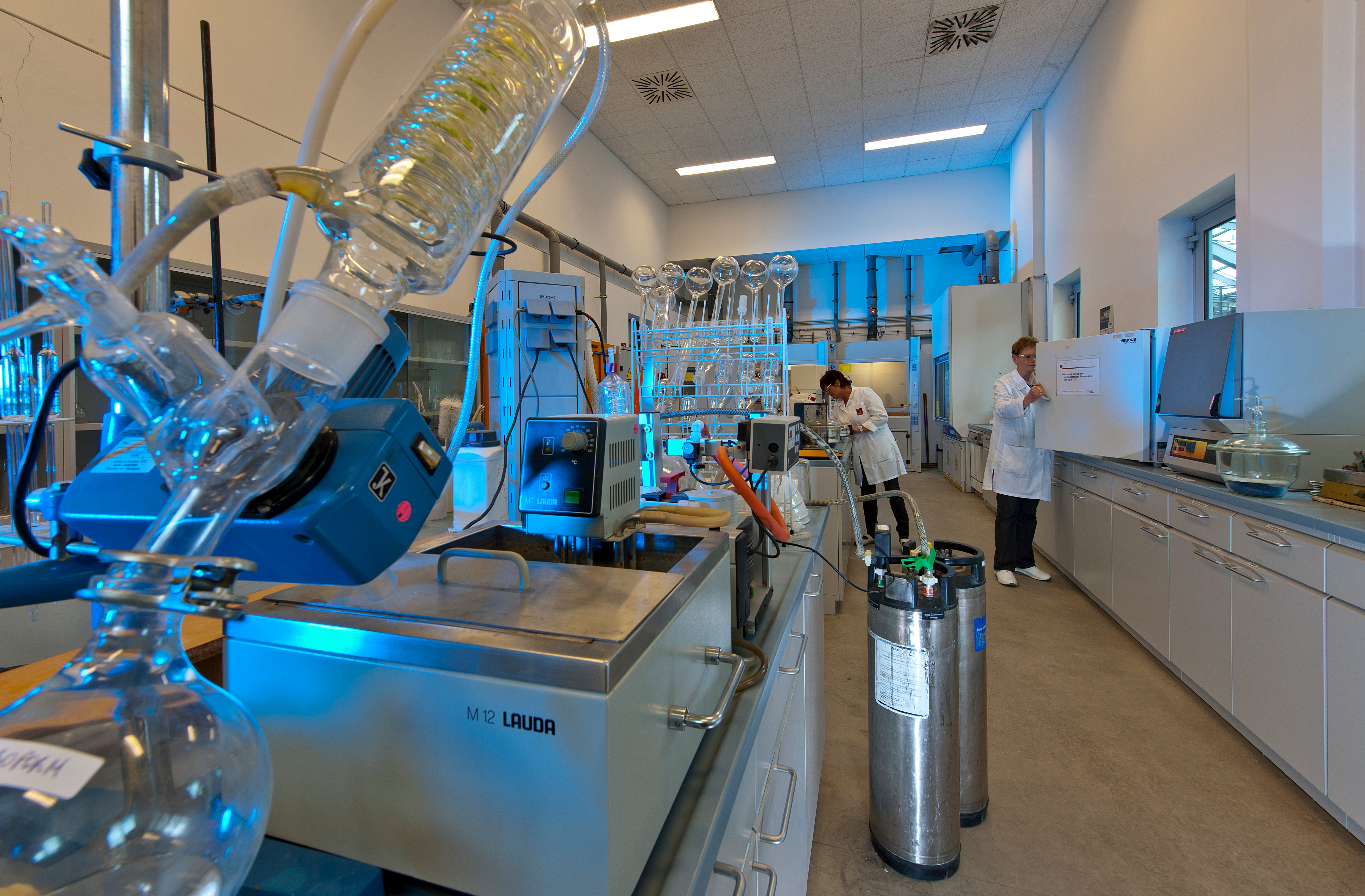 Kiwa laboratory employees working in a modern laboratory equipped with advanced scientific apparatus and equipment, conducting experiments wearing lab coats