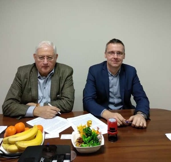 Du asmenys pasirašo bendradarbiavimo dokumentus prie stalo