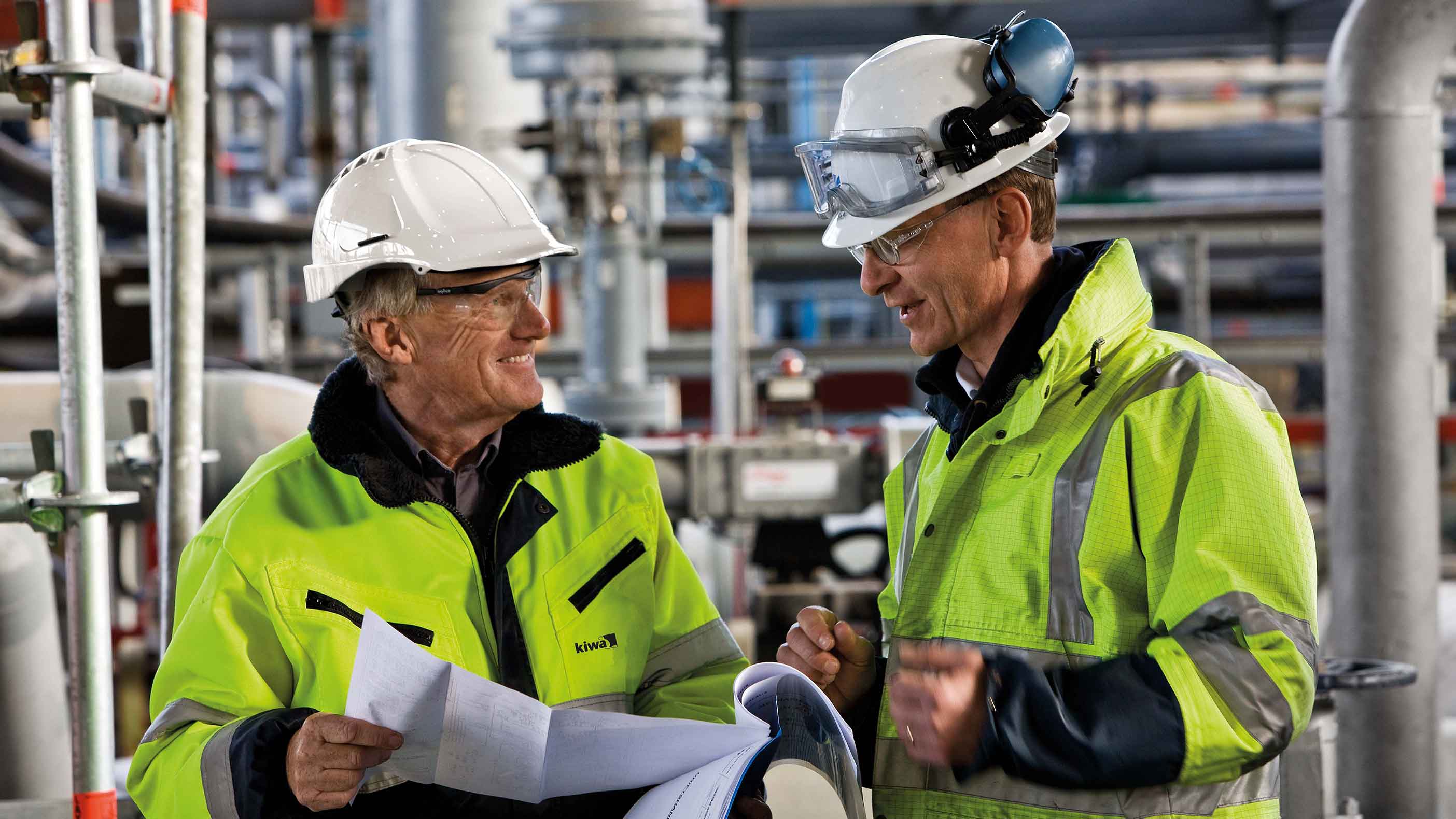 Män med ritningar som ler.