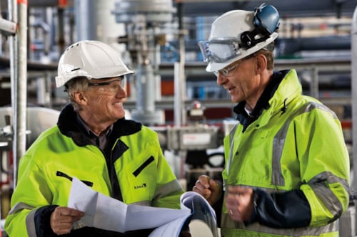 Män med ritningar som ler.