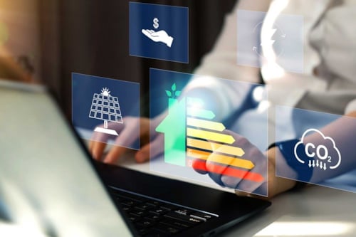 Personer arbetar vid en laptop med överlagrade ikoner för solenergi, energieffektivitet och koldioxidutsläpp, koncept för hållbar energi och miljö in en energideklaration..