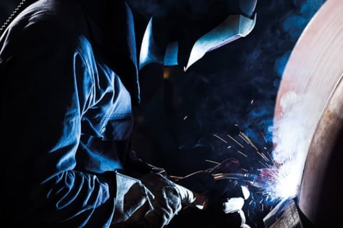 Svetsare svetsar på ett tryckkärl eller cisternliknande föremål.