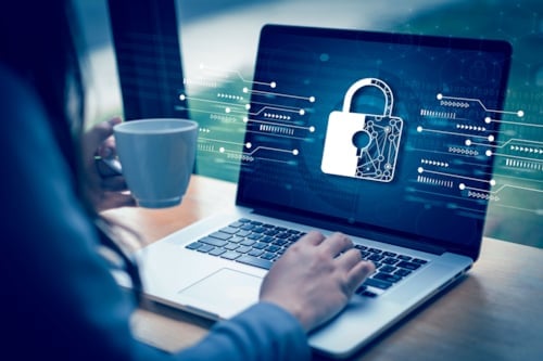Person som använder en bärbar dator med en säkerhetsikon i form av ett hänglås på skärmen.