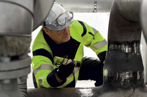 Arbetare inspekterar rör och industripipor i en teknisk anläggning.