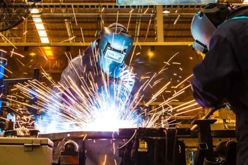 Svetsarbete utförs av två svetsare i en industrilokal.