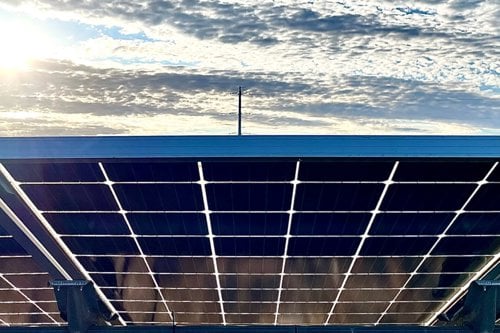 Solar panels on a rooftop under a bright sky with scattered clouds