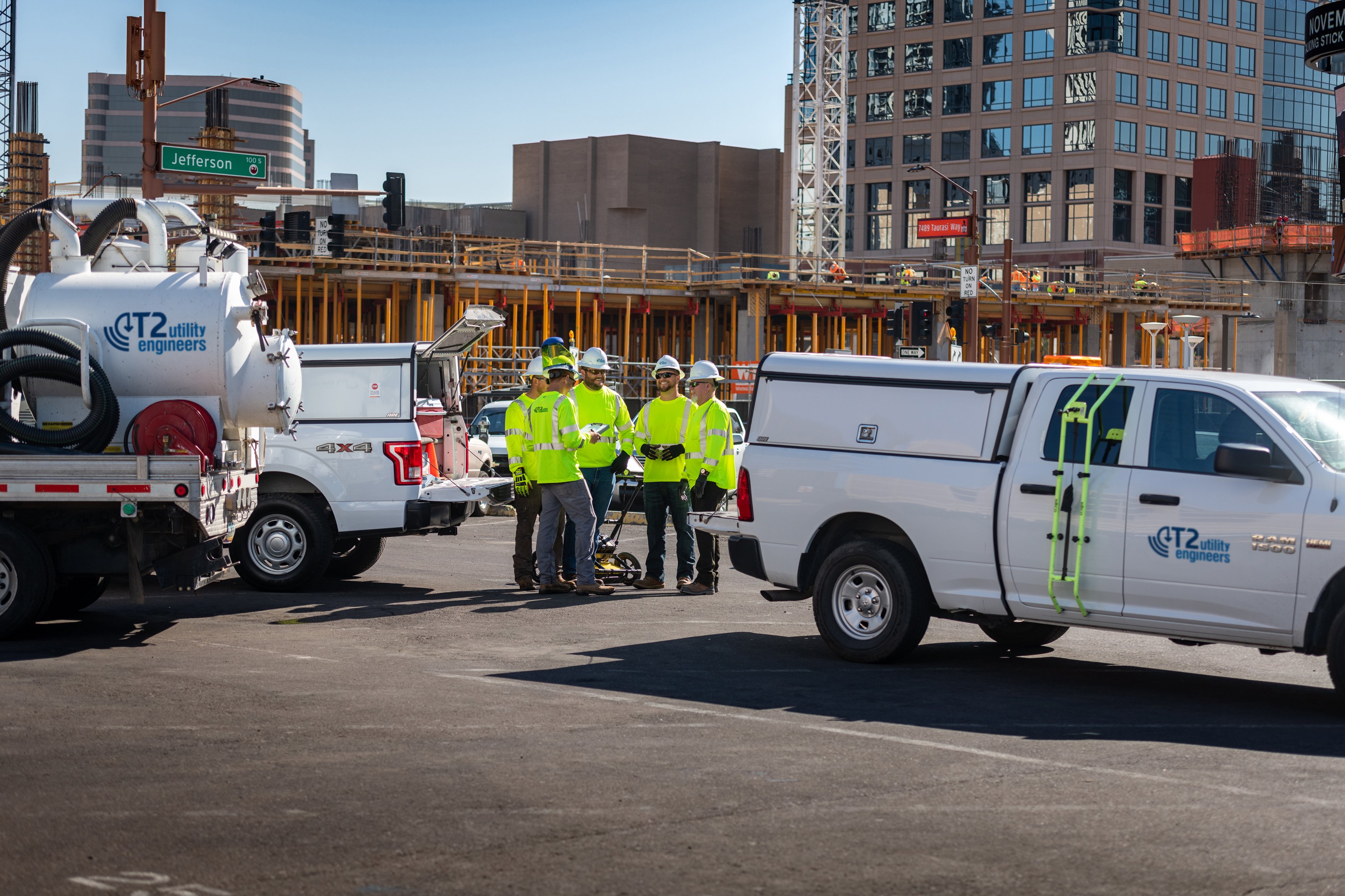 Kiwa engineers in high-visibility jackets standing beside utility trucks at an urban job site.