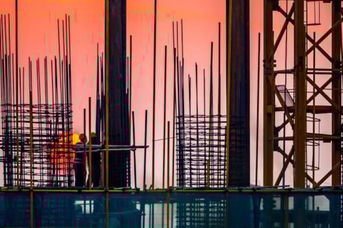 Steel building site with builders and sunset